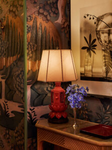 Vintage artisanal lamp on table, with a small flower stand, radiates exquisite elegance.