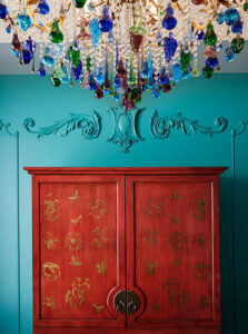 Sophisticated wall design above wardrobe, enhanced by a ceiling-suspended chandelier, exudes elegance.