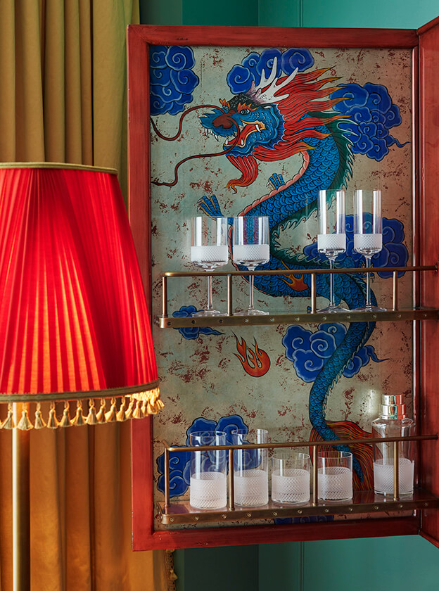 Various crystal wine glasses are neatly arranged on the rack, complemented by a dragon painting backdrop.