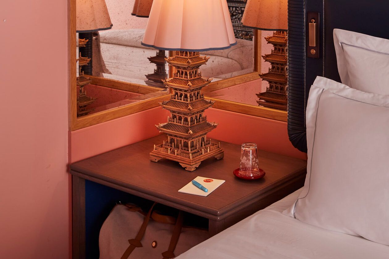 Antique lamp handcrafted and positioned on the bedside table, its reflection captured in the mirror.