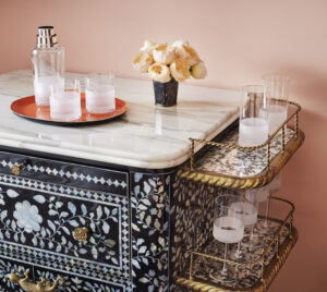Bottle and glass tray on table, complemented by an array of crystal glasses on side rack.
