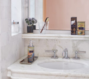 A pristine white marble washbasin, equipped with handwash and fragrances, enhances a fresh and clean ambiance.