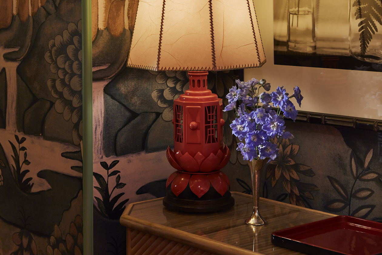 Antique handcrafted lamp on the table, accompanied by a small flower stand, exuding elegance.