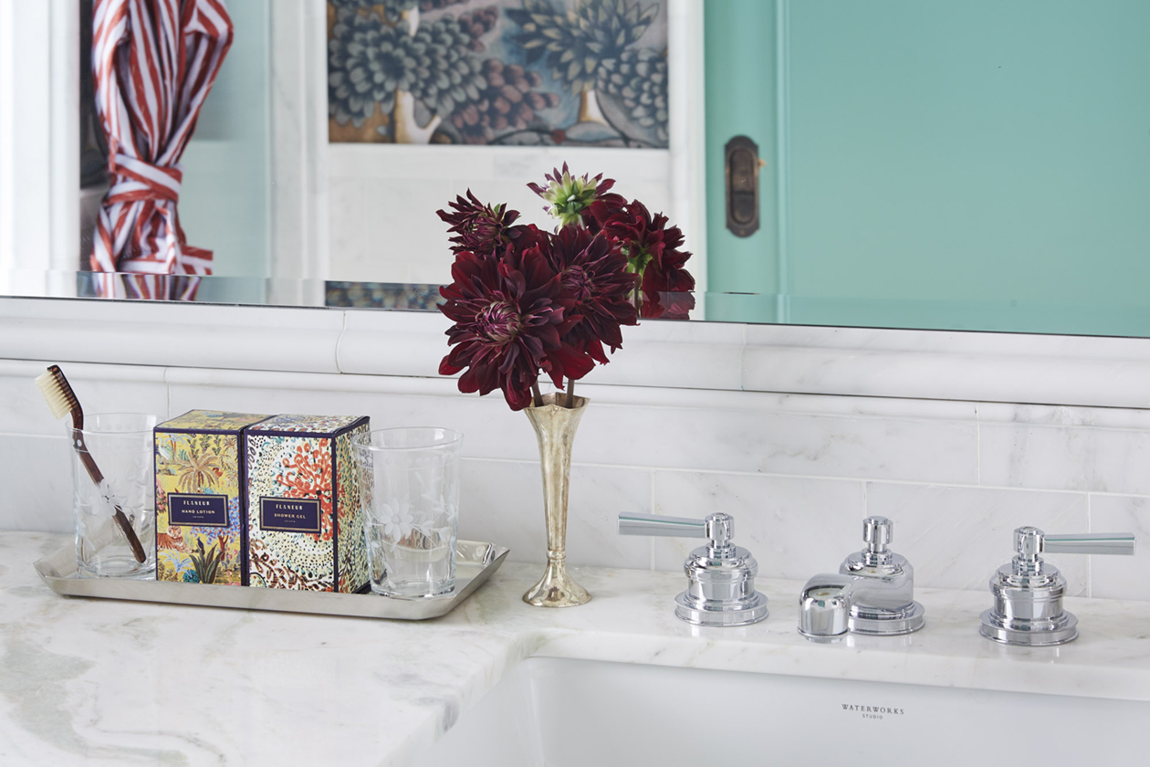 A white marble washbasin, adorned with handwash, a small flower, and fragrances, creating a refreshing atmosphere.