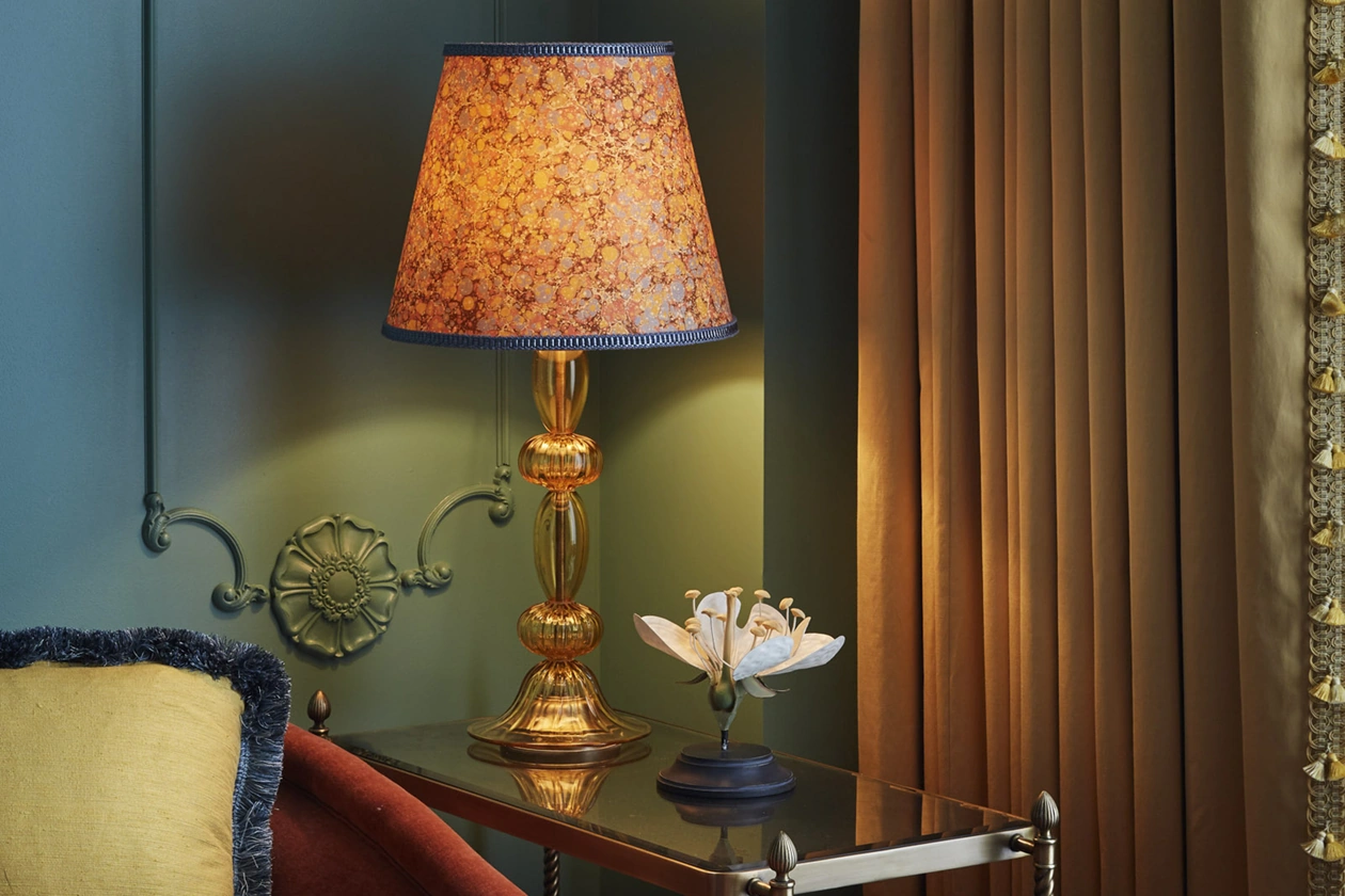 Antique crystal lamp on table, complemented by a stand holding a beautiful flower.