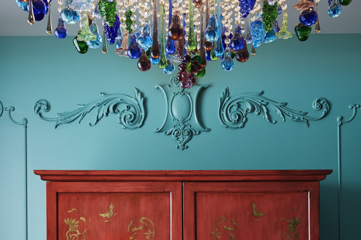 Elegant wall design above wardrobe, adorned by a chandelier suspended from the ceiling.