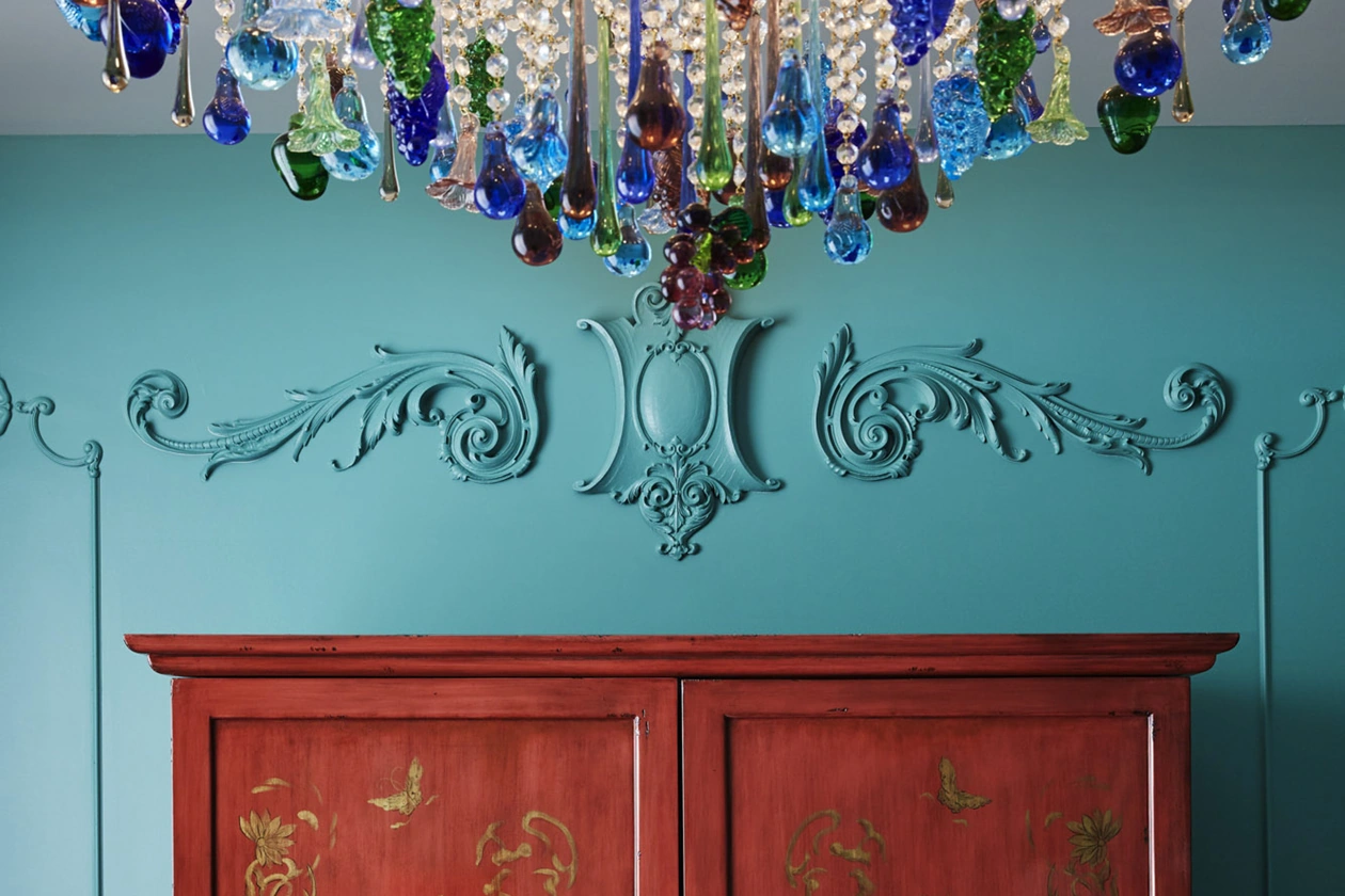 Elegant wall design above wardrobe, adorned by a chandelier suspended from the ceiling.