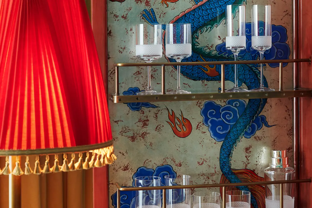 Various crystal wine glasses are neatly arranged on the rack, complemented by a dragon painting backdrop.