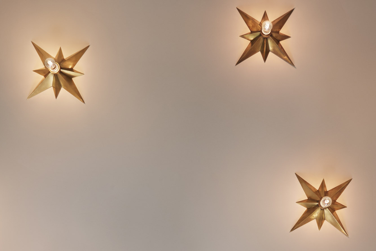 Small chandelier with star design and illuminated bulbs suspended from the ceiling.