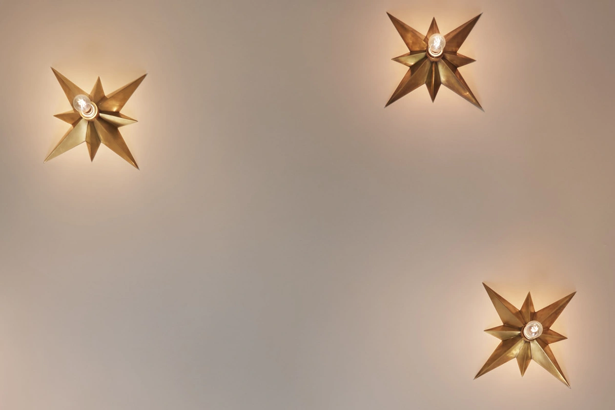 Small chandelier with star design and illuminated bulbs suspended from the ceiling.