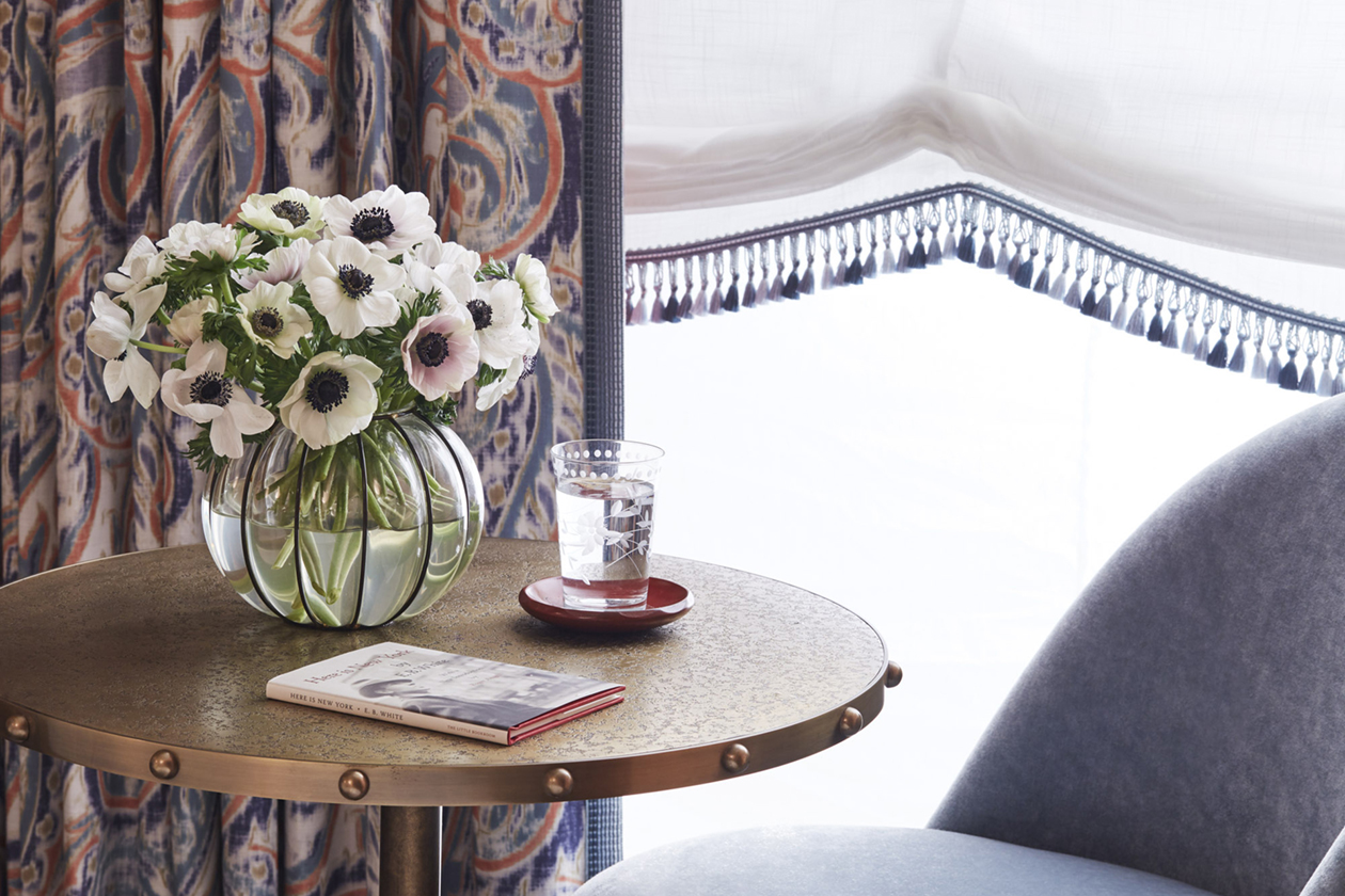 Elegant glass flower vase with water glass and a notebook grace the round table with charm.