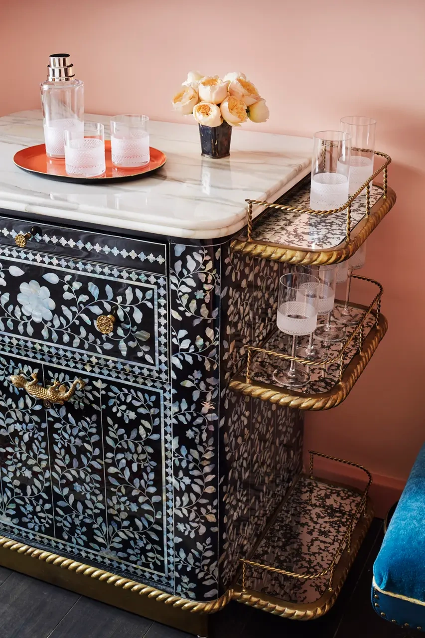 Tray with bottle and glasses on table, alongside various crystal glasses on side rack.