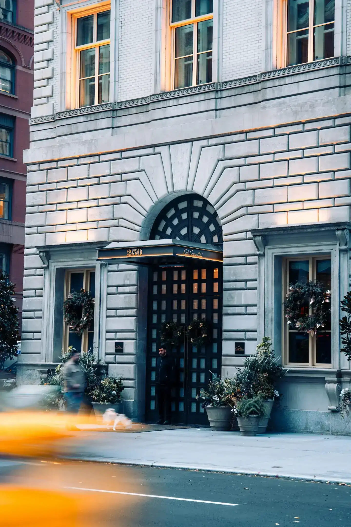 Exterior entrance of Café Carmellini in NYC: A stylish café with a welcoming entrance adorned with modern signage and outdoor seating.