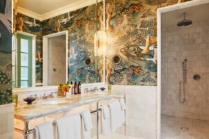 Bathroom with a white marble finish, a large mirror above the washbasin, and towels hanging beneath the iron rod.