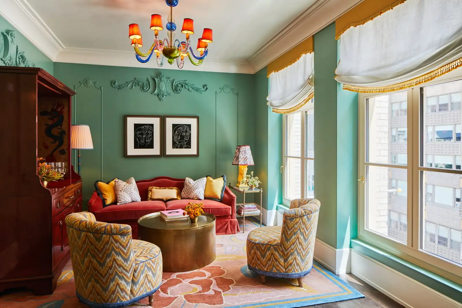 Tastefully organized living area with diverse sofas, golden coffee table, and a colorful chandelier hanging from the ceiling.
