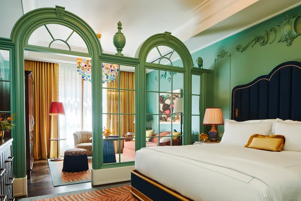 Tastefully organized bedroom: bed with table lamp, sofa set near the window, creating inviting ambiance.