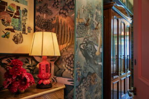 Lovely vase on table, accompanied by a table lamp, with a portrait above.