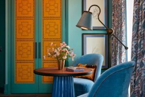 Between two sofas, a table holds a lovely vase, notebooks, lit by a standing lamp.