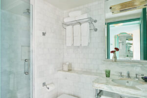 Tastefully organized bathroom: tidy towel on rack, mirror above washbasin adorned with nearby flower vase.