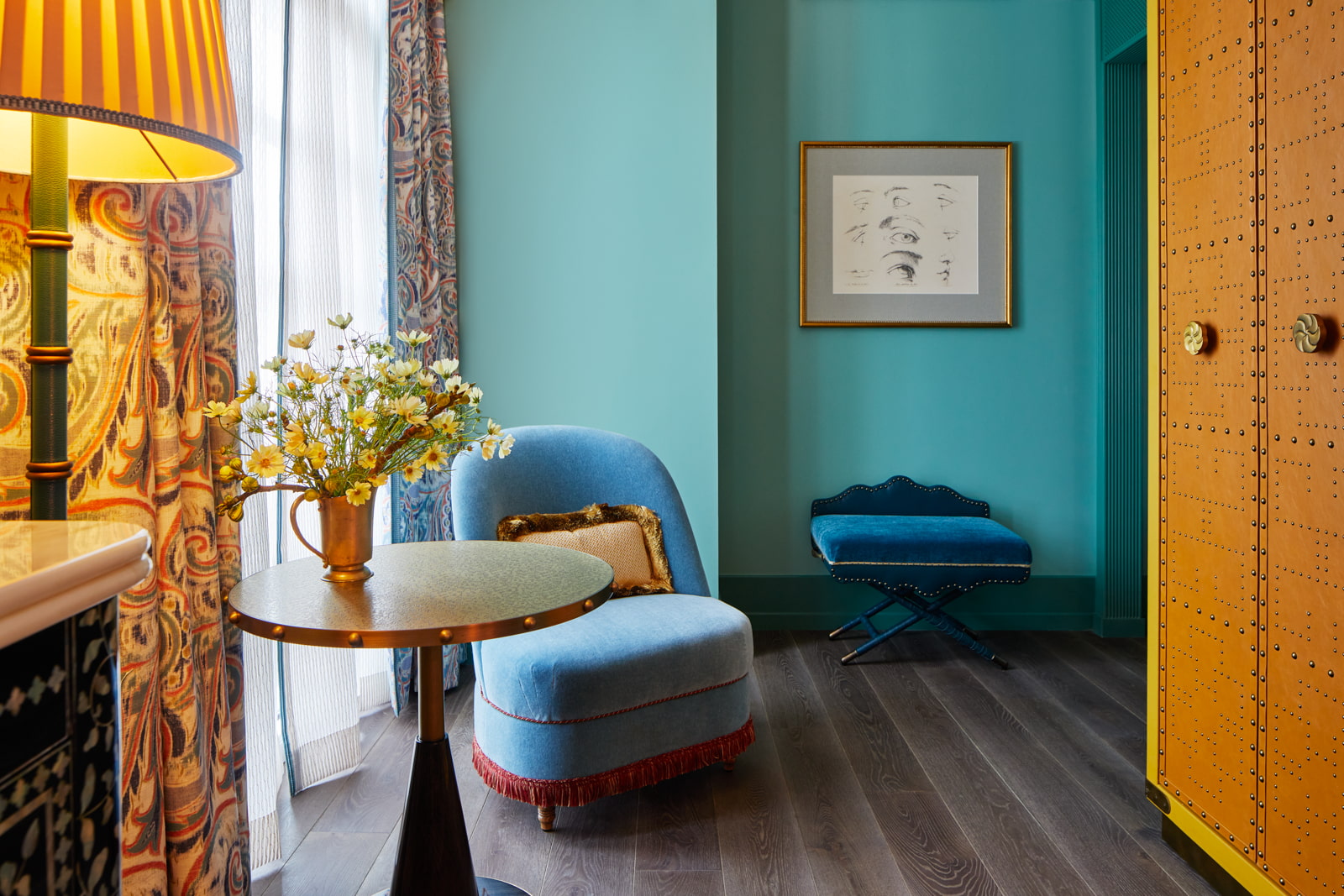 Sofa near window, table with vase, portrait hung on blue wall, forming an inviting ambiance.