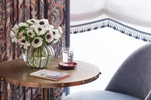 Elegant glass flower vase with water glass and a notebook grace the round table with charm.