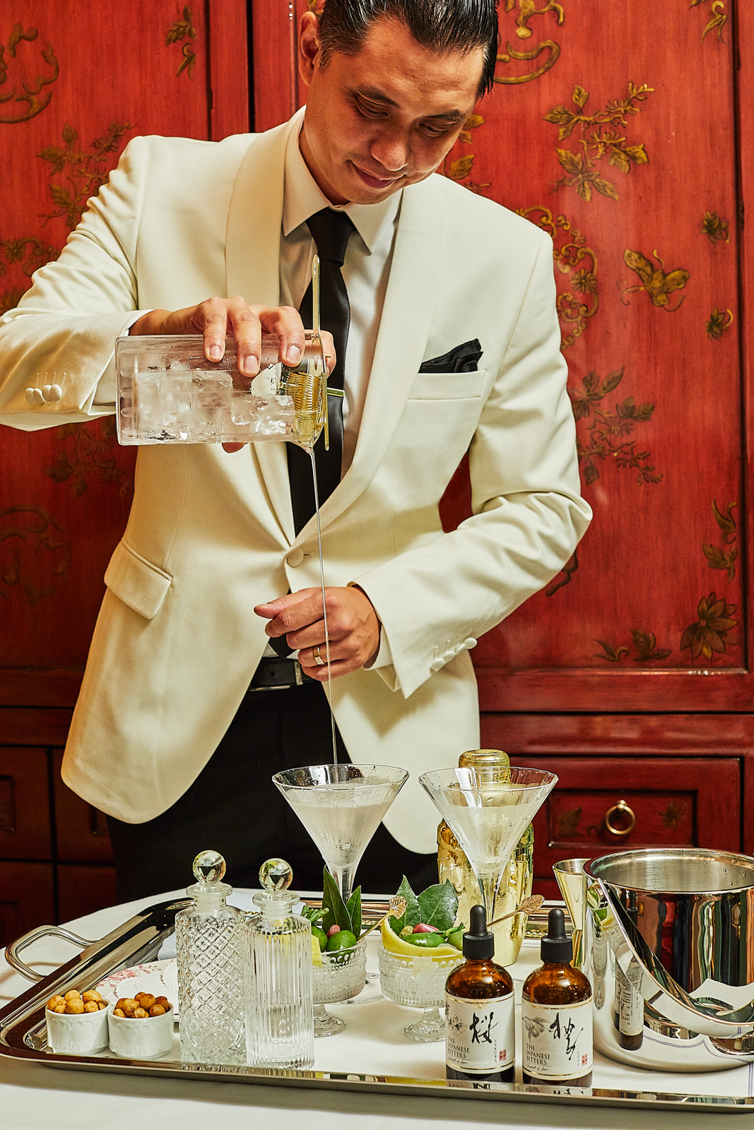 A man in a white suit pouring a drink.