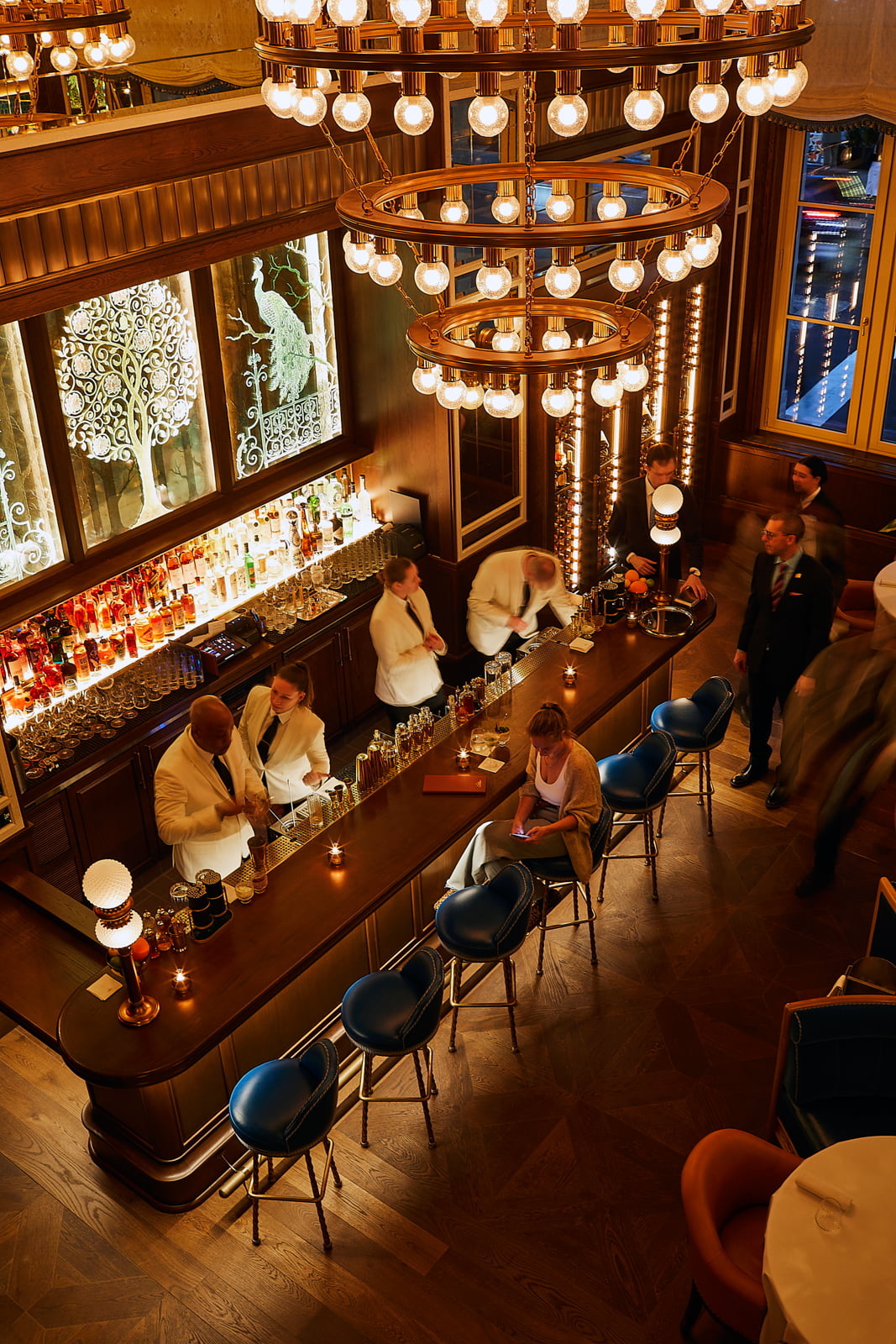 A bar with a long counter and a few people sitting at it, located at Cafe Carmellini