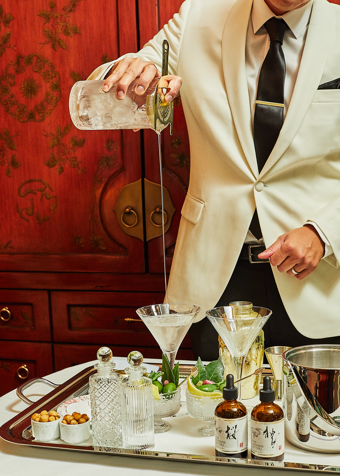 A man in a suit pouring a drink on a tray at The Fifth Avenue bar.