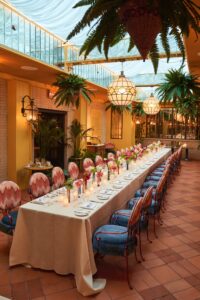 A long dining table with chairs is set and ready for the party.