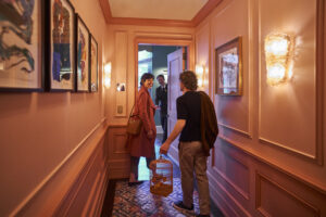 A couple is about to enter their room while someone waits for them.