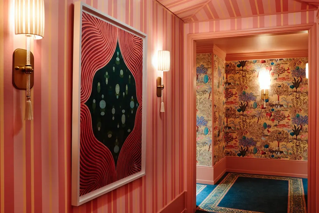 A beautifully painted corridor with a mounted portrait and a glowing lamp.