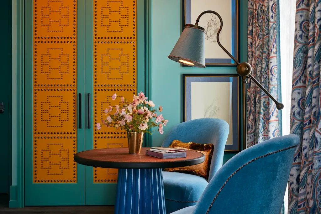 Two cozy chairs with a coffee table and a lamp placed beside them.