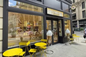 Yellow chairs and tables are neatly arranged at the entrance of "Venchi" ice cream shop.