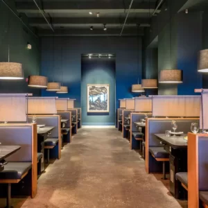 A well-arranged restaurant seating area with a portrait mounted on a blue wall.