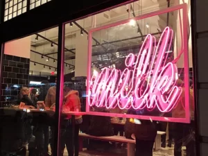 A pink neon signboard with the text "Milk" glowing in the glass window.