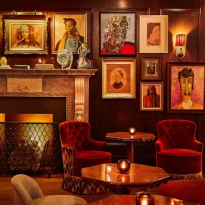 A well-arranged seating area with many chairs and tables, and beautifully mounted portraits.