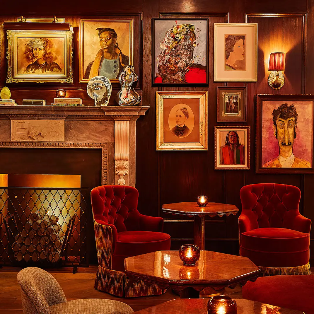 A well-arranged seating area with many chairs and tables, and beautifully mounted portraits.