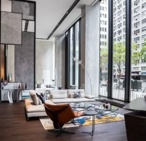 A luxurious living space with an L-shaped sofa set and a brown cozy chair near the window.