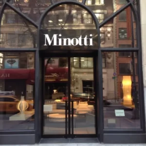 The glass entrance door of a building displays "Minotti" prominently.