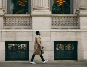 A man in a long coat walks along the footpath beside The Fifth Hotel.