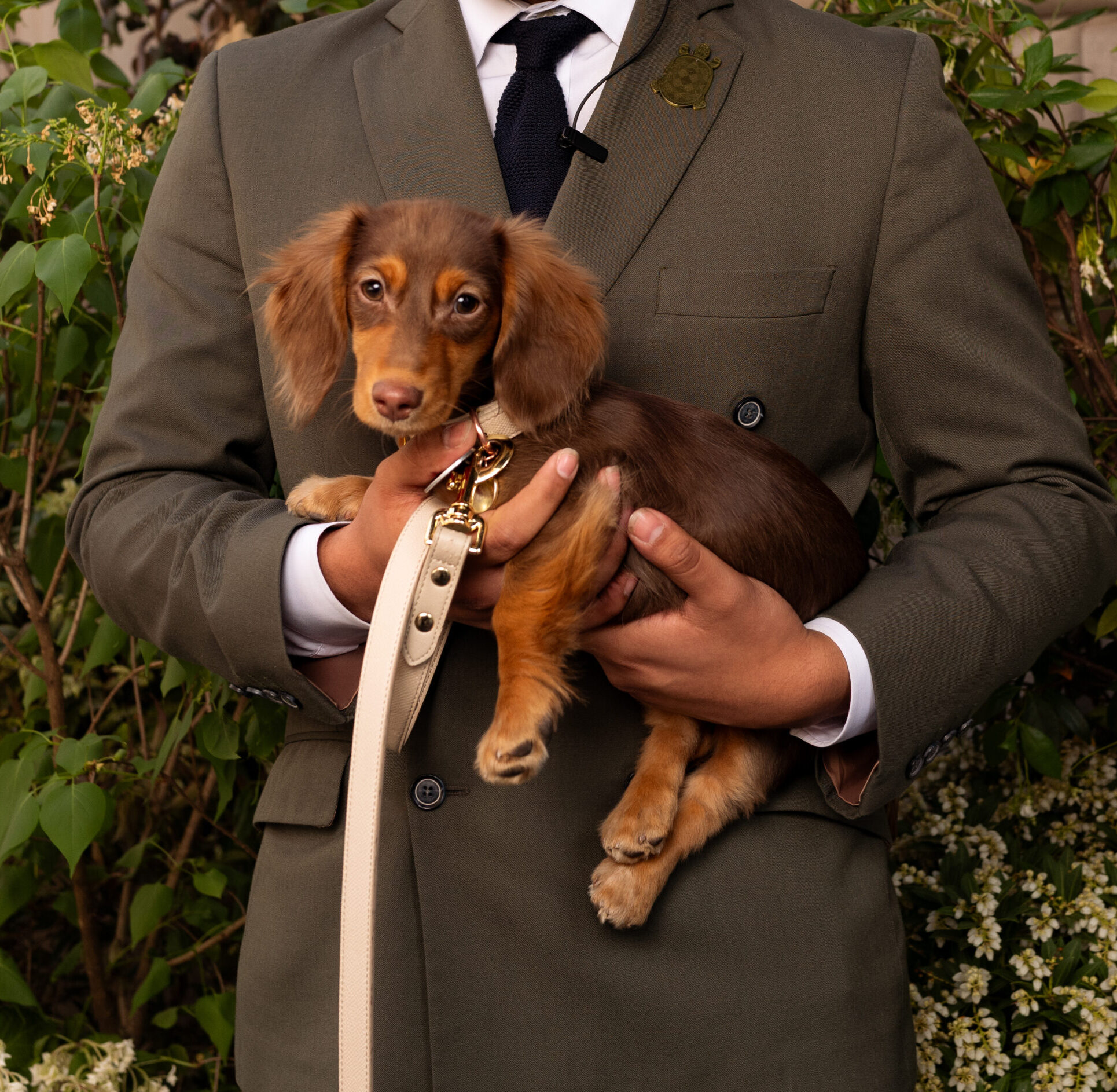 A man holding his dog while posing for a photo at The Fifth Avenue hotel, capturing a warm and stylish moment.