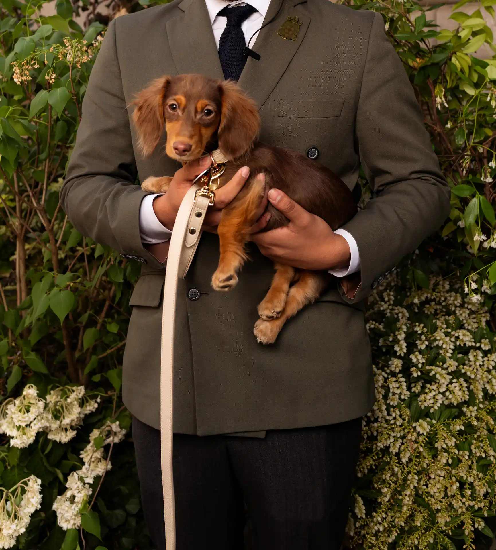 A man holding his dog while posing for a photo at The Fifth Avenue hotel, capturing a warm and stylish moment.