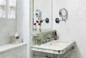 Marble bathroom sink with mirror, flowers, and chrome fixtures in a clean, luxurious setting