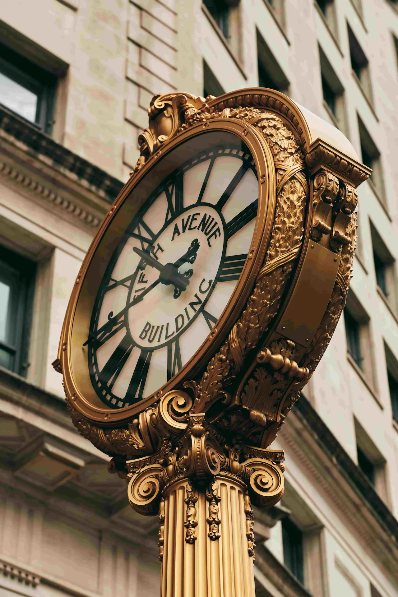 A large clock stands on the street in front of The Fifth Avenue Building.
