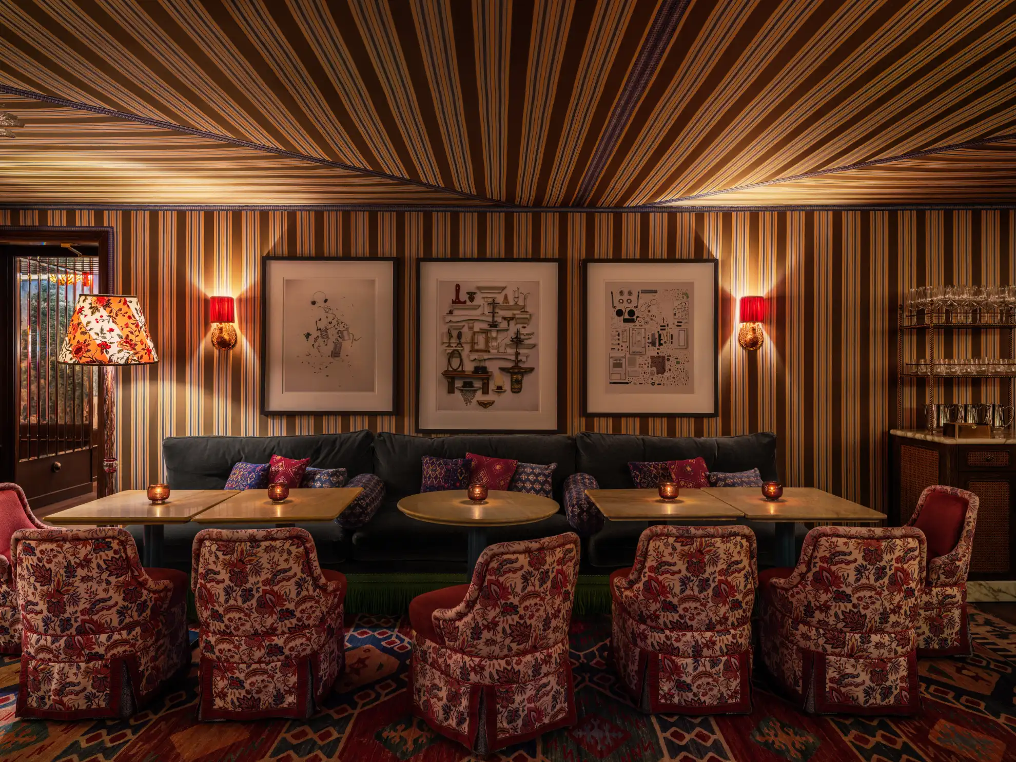 Bold living room with teal walls, red velvet sofa, floral rug, and playful chandelier.