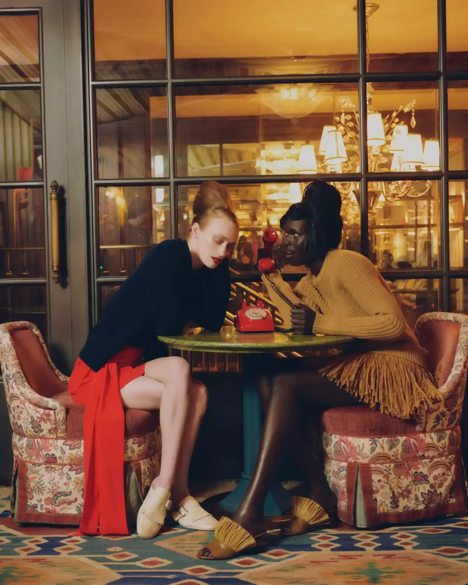 Two women elegantly seated at The Fifth Avenue hotel café, enjoying conversation in a stylish setting