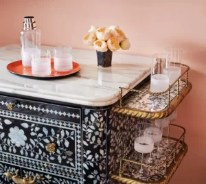 Bottle and glass tray on table, complemented by an array of crystal glasses on side rack.